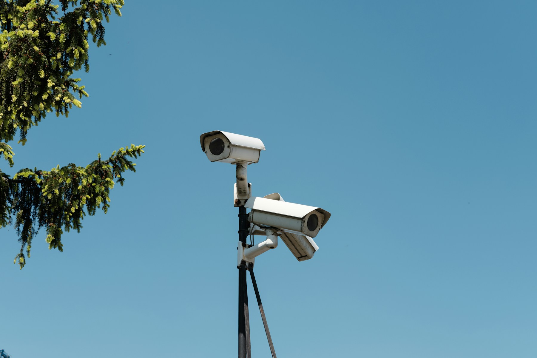 Two security cameras mounted on a pole against a blue sky; representative industry photograph