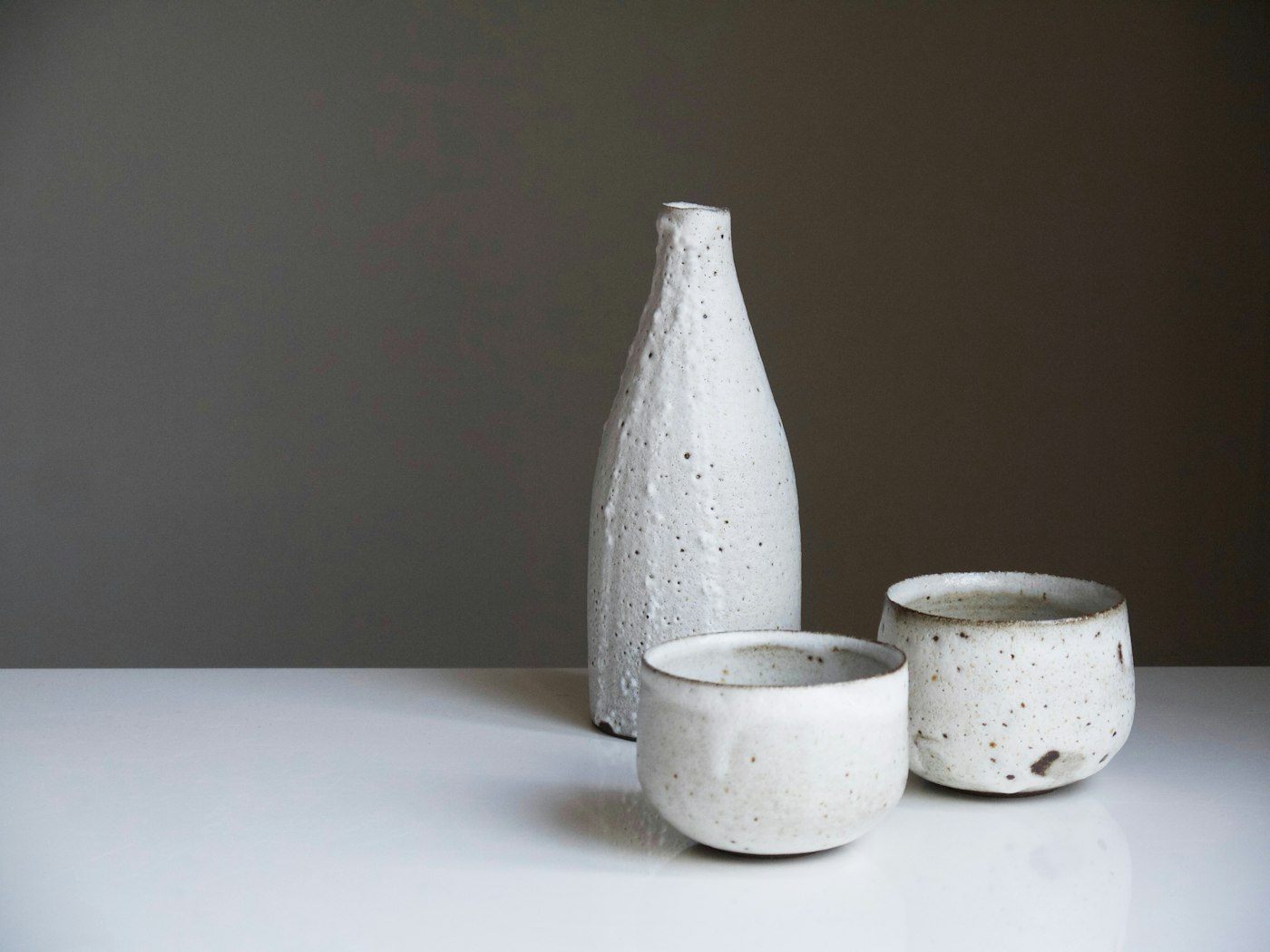 Two finished ceramic cups and a bottle with a speckled glaze
